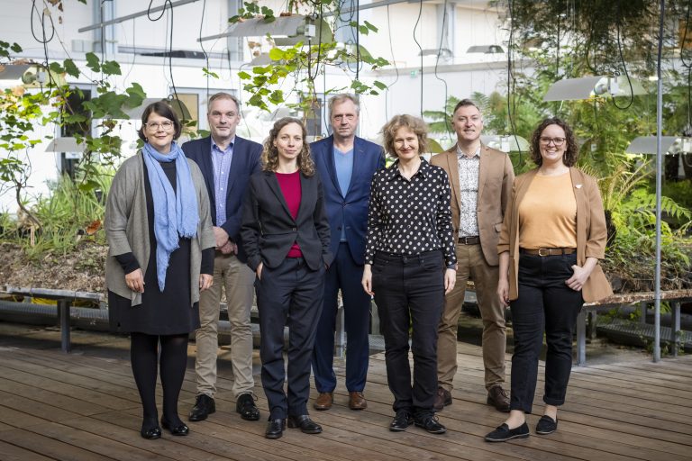 Mitglieder des Vorstands und der Geschäftsstelle, insgesamt sechs Personen, stehen mit der stellvertretenden Direktorin des Jüdischen Museums Berlin zusammen. Im Hintergrund sind Pflanzen zu sehen.
